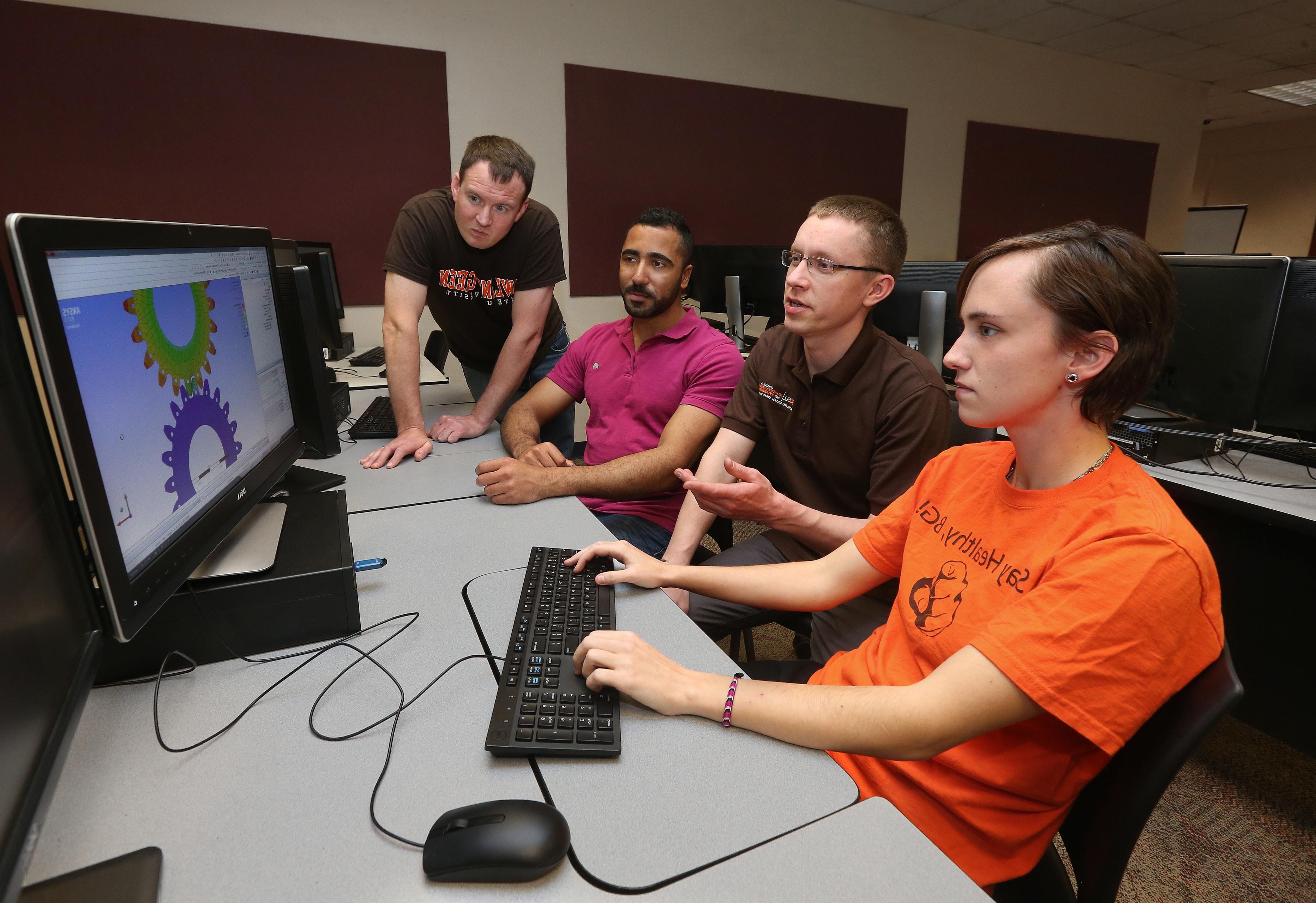 Three male 和 one female in the master’s program in the BGSU technology management program with a focus in quality systems work together in front of a computer.